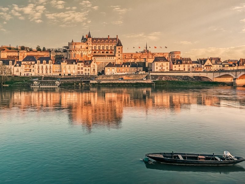 The Château Royal d'Amboise above the Loire at sunset, a flat-bottomed boat moored in the foreground