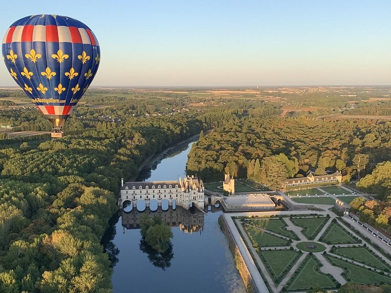 A hot-air balloon at sunrise above the Cher, Château de Chenonceau and its gardens below